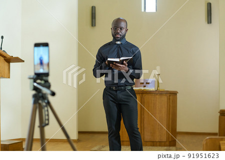 Confident young pastor of evangelical church with open Holy Bible 91951623