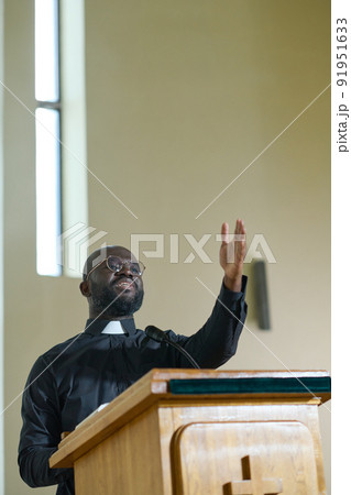 Young confident priest in black shirt with clerical collar standing by pulpit 91951633