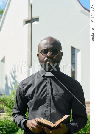 African American preacher in black shirt with clerical collar holding Bible 91951727