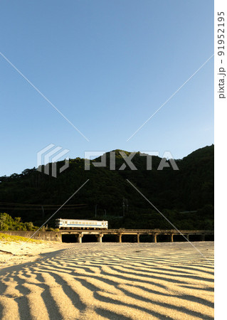 朝焼けの宮崎県日南市山王浜の波打ち際の隈谷川橋梁を走る日南線キハ40 91952195