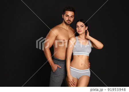 Young couple in grey sportive underwear on black background Young couple in grey sportive underwear on black background 91953948