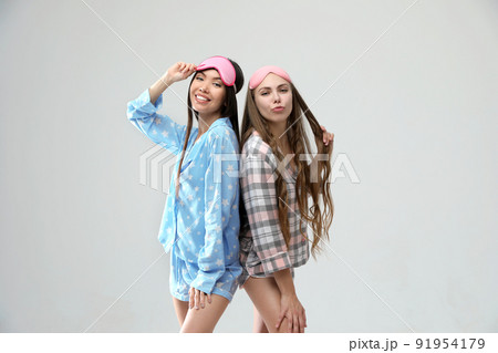 Beautiful women in pajamas on light grey background. Bedtime 91954179