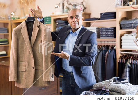 Seller offering suit jacket in menswear boutique 91957159