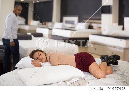 Young latin american woman sleeping on mattress in furniture shop Young latin american woman sleeping on mattress in furniture shop 91957493
