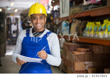 Smiling worker taking notes during inventory in hardware store Smiling worker taking notes during inventory in hardware store 91957603