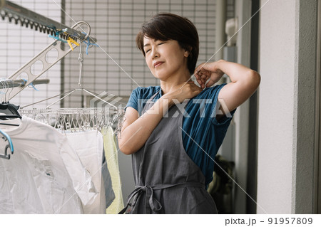 家事をしながら肩こり・ストレス・疲労を感じる主婦 91957809