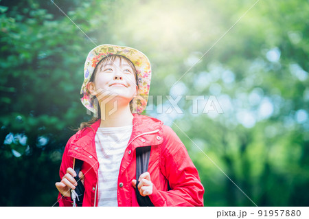 強い日差しの中、緑のあふれる山を歩く女性 91957880