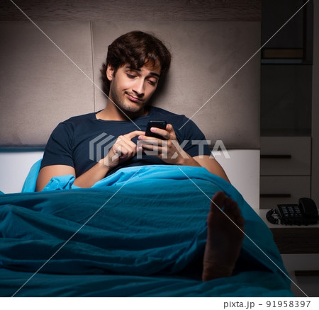 Young man texting on mobile late at night 91958397