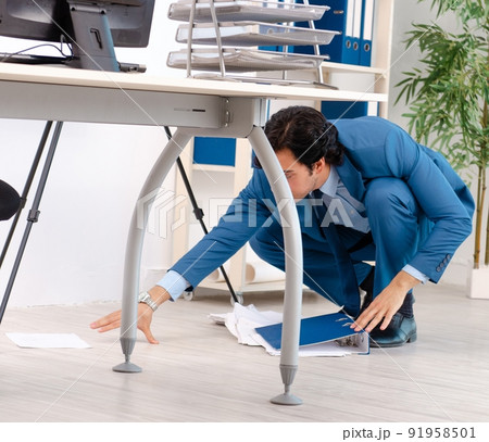 The young handsome male employee with too much work in the offic The young handsome male employee with too much work in the offic 91958501
