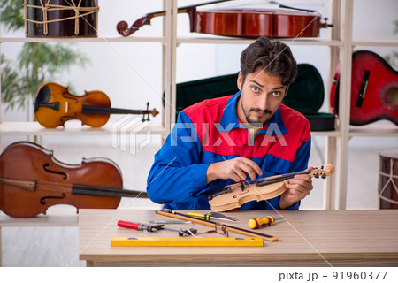 Young man repairing musical instruments at workshop 91960377