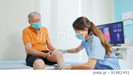 doctor examining patient knee 91962491