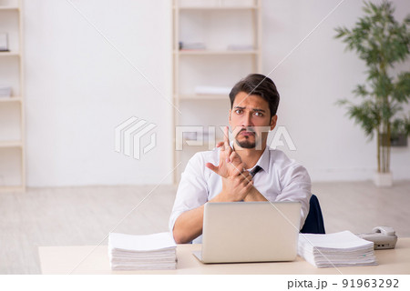 Young male employee unhappy with excessive work in the office 91963292