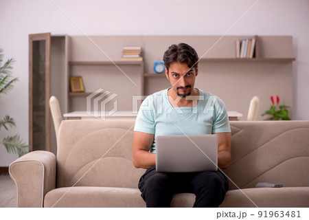 Young man sitting on the sofa with computer at home 91963481