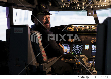 Portrait of professional aviator using cockpit dashboard command to takeoff on international flight. Male pilot flying aircraft jet with control panel buttons and power engine lever. Portrait of professional aviator using cockpit dashboard command to takeoff on international flight. Male pilot flying aircraft jet with control panel buttons and power engine lever. 91967234