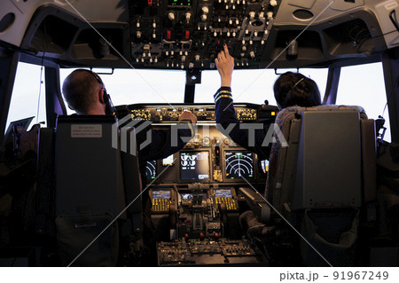 Captain and woman copilot getting ready to fly airplane and takeoff with dashboard navigation in cockpit command. Airline crew fixing altitude level and with control panel buttons, flying plane. Captain and woman copilot getting ready to fly airplane and takeoff with dashboard navigation in cockpit command. Airline crew fixing altitude level and with control panel buttons, flying plane. 91967249