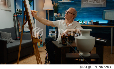 Paralyzed man with health condition drawing modern art model of authentic vase, using artistic tools in wheelchair. Artist with physical disability creating professional artwork sketch. 91967263