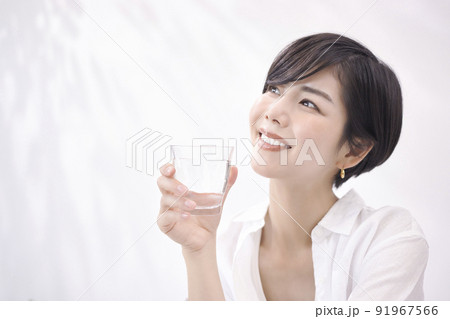 リビングで水を飲む若い女性 91967566