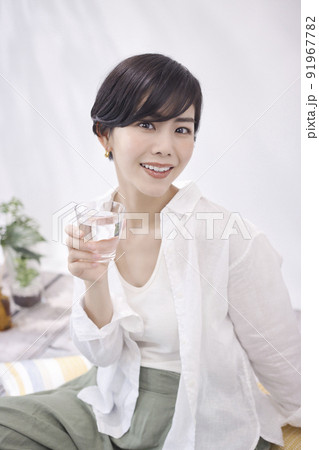 リビングで水を飲む若い女性 91967782