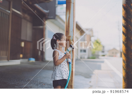 夏にホースの水で遊ぶ女の子 91968574