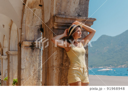 Summer photo shoot on the streets of Kotor, Montenegro. Beautiful girl in yellow dress and hat. smiling tourist girl with hat. Spectacular view of Montenegro with copy space. fashion outdoor photo of 91968948