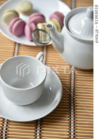 Porcelain teapot with a cup of tea and macaroons 91969038
