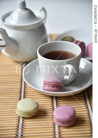 Porcelain teapot with a cup of tea and macaroons 91969042