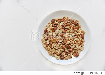 Fried delicious peanuts on a white plate close-up Fried delicious peanuts on a white plate close-up 91970701