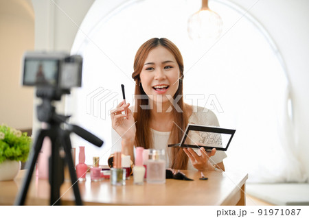 Attractive young Asian female beauty blogger giving advice, making a makeup tutorial video. Attractive young Asian female beauty blogger giving advice, making a makeup tutorial video. 91971087