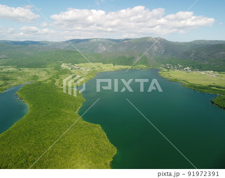 Aerial view on water reservoir at mountain valley covered with green spring forest. Beautiful view from above on smooth blue surface of mountain lake among highlands. Drone point of view. Nobody 91972391
