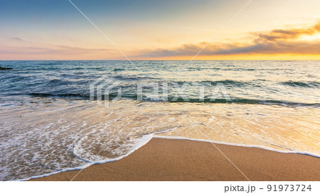 sandy beach at sunrise. beautiful seascape background. calm waves washing the shore. clouds glowing in morning light. summer vacation and relaxing recreation concept sandy beach at sunrise. beautiful seascape background. calm waves washing the shore. clouds glowing in morning light. summer vacation and relaxing recreation concept 91973724