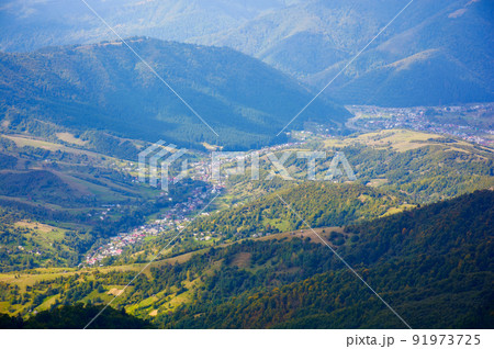 mountain landscape on a sunny autumn morning. village in the distant valley. view from the top of a forested hill mountain landscape on a sunny autumn morning. village in the distant valley. view from the top of a forested hill 91973725