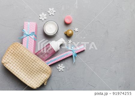 Christmas flat lay with makeup cosmetic products in cosmetic bag on colored background. Top view New year Beauty concept 91974255