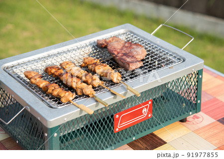 BBQでステーキと焼き鳥を焼いている BBQでステーキと焼き鳥を焼いている 91977855
