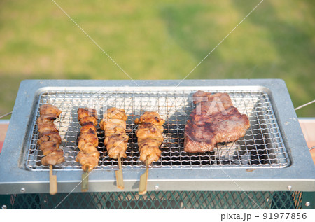 BBQでステーキと焼き鳥を焼いている BBQでステーキと焼き鳥を焼いている 91977856
