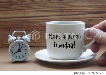 Morning greeting concept - Have a great Monday text on coffee cup with alarm clock on wooden table. 91978573