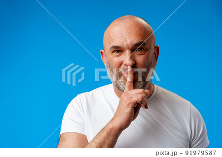 Middle age man wearing t-shirt over blue wall asking to be quiet Middle age man wearing t-shirt over blue wall asking to be quiet 91979587