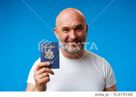 Middle age man holding passport with a happy face against blue background Middle age man holding passport with a happy face against blue background 91979588