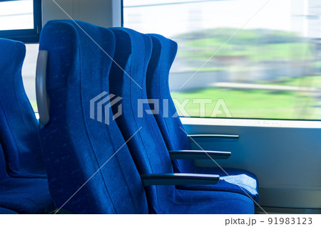 interior of commuter passenger train car, row of chairs and a motion-blurred landscape outside the window interior of commuter passenger train car, row of chairs and a motion-blurred landscape outside the window 91983123