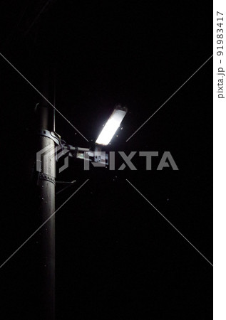 電柱に設置されたライトに多数の虫が群がっている夏の夜間の屋外の光景を高感度で撮影した画像 電柱に設置されたライトに多数の虫が群がっている夏の夜間の屋外の光景を高感度で撮影した画像 91983417