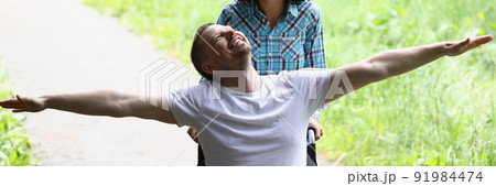 Disabled man sit in wheelchair, wife drive him behind Disabled man sit in wheelchair, wife drive him behind 91984474