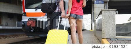 Woman and man with yellow suitcase on train station wait for express train Woman and man with yellow suitcase on train station wait for express train 91984524