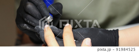 Nail master using electrical equipment to clean client nails in modern beauty studio 91984525