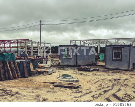 construction site of an industrial complex. small houses for builders with windows at the site of the construction of the foundation. dirt on the street, building material lies construction site of an industrial complex. small houses for builders with windows at the site of the construction of the foundation. dirt on the street, building material lies 91985568