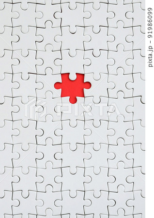 The texture of a white jigsaw puzzle in an assembled state with one missing element forming a red space 91986099