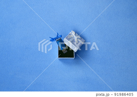 Brilliant blue usb flash memory card with a blue bow lies in a small gift box in blue with a small bow on a blanket of soft and furry light blue fleece fabric. Classic female gift memory card design Brilliant blue usb flash memory card with a blue bow lies in a small gift box in blue with a small bow on a blanket of soft and furry light blue fleece fabric. Classic female gift memory card design 91986405