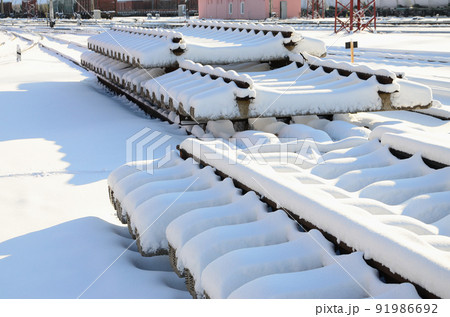 A lot of old rails and sleepers are stacked in a railway warehouse in winter. The concept of renewing a worn-out railway track A lot of old rails and sleepers are stacked in a railway warehouse in winter. The concept of renewing a worn-out railway track 91986692