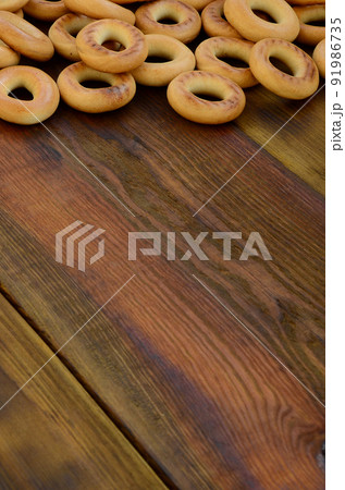 A lot of fresh yellow bagels lie on the surface of the old dark wood. A popular kind of flour products. One of the traditional Russian treats for tea 91986735