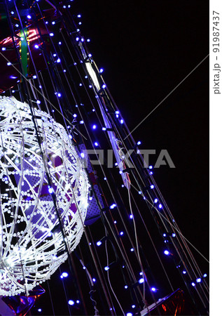 Fragment of the New Year tree. A lot of round lights of blue color are located on a conical frame 91987437
