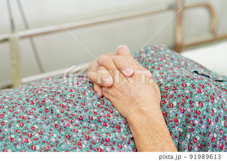 Asian elder senior woman patient holding bed rail while lie down with hope waiting her family in hospital. Asian elder senior woman patient holding bed rail while lie down with hope waiting her family in hospital. 91989613