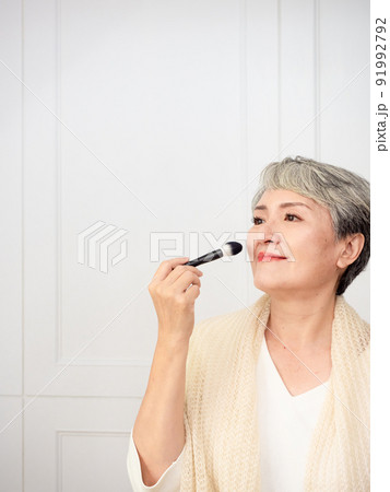 Portrait of mature asian woman 50s with holding make up brush. 91992792